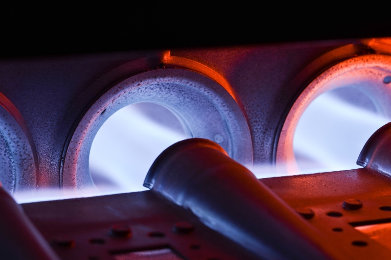 Don't Forget Your Fall Furnace Tune-Up! Closeup Shot Of Home Furnace Burner Ignited With Crimson Blue Flame.